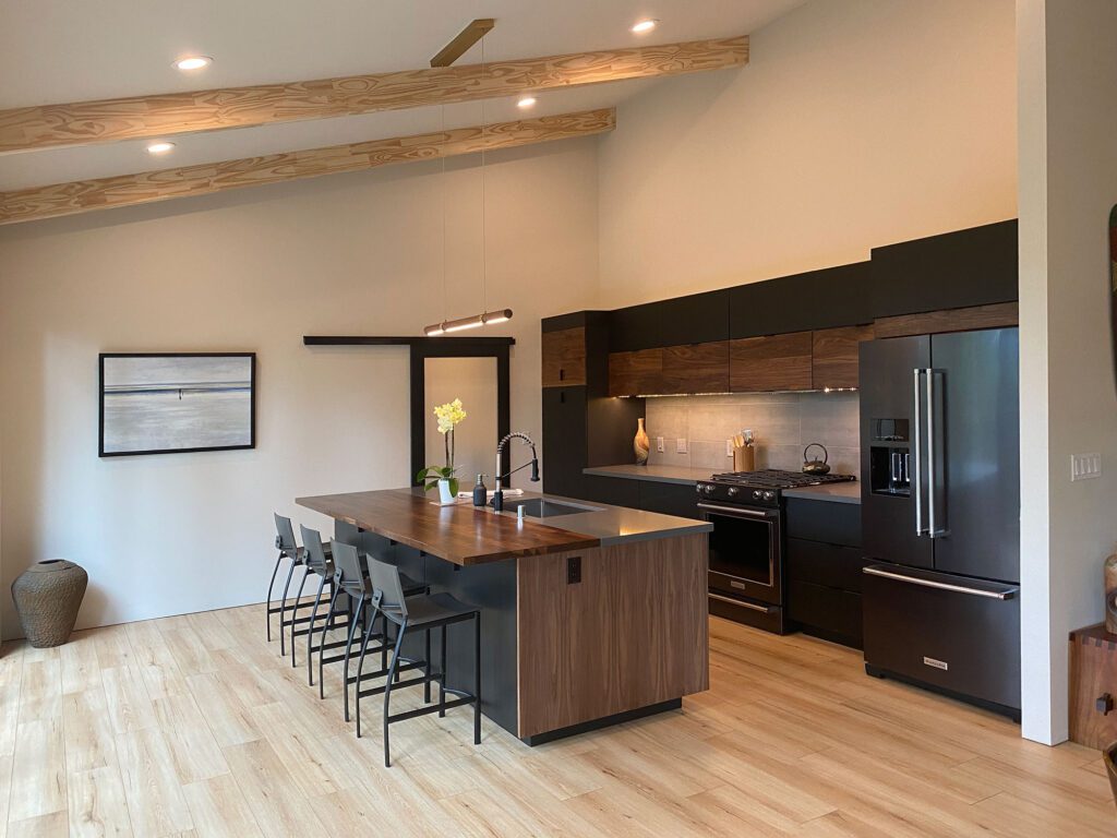 A kitchen with wooden floors and black cabinets.