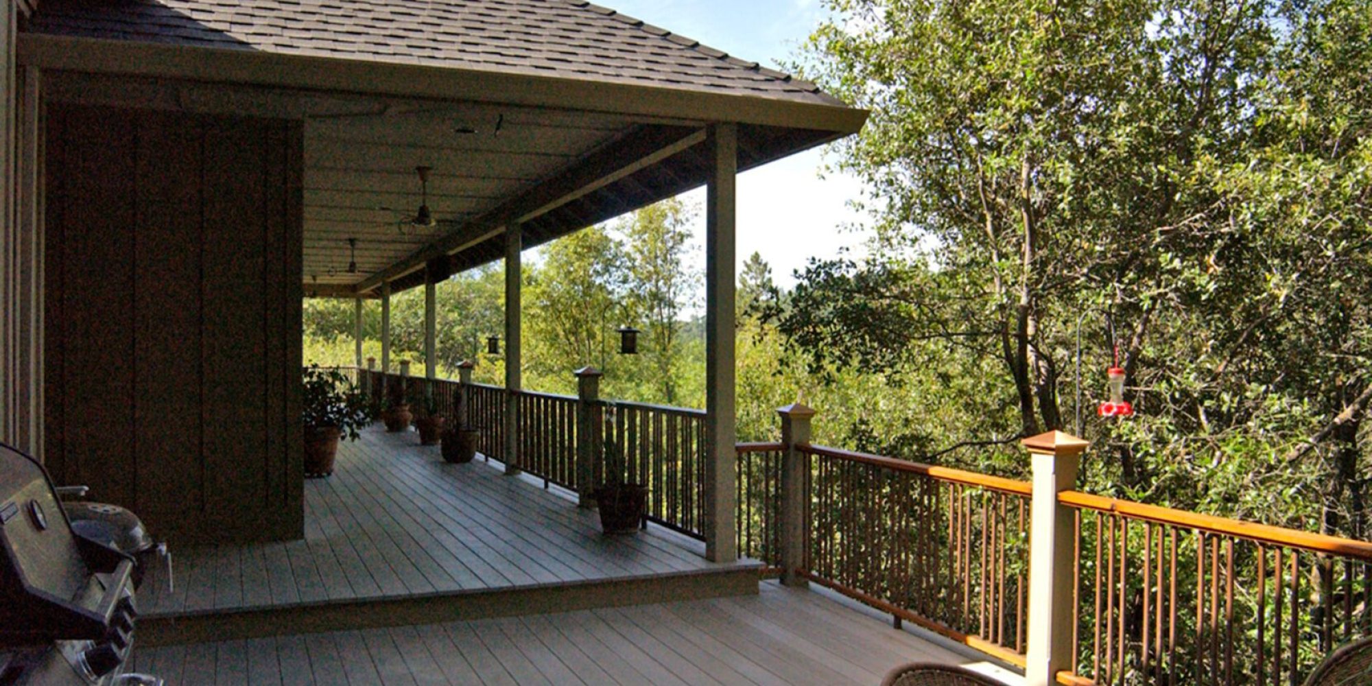 A large deck with chairs and trees in the background.